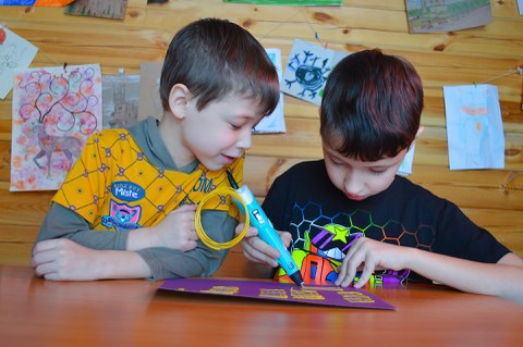 2 Jungs gestalten ein Bild mit einer Klebepistole