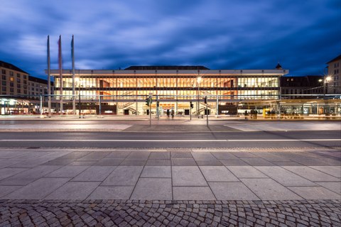 Das Foto zeigt den Dresdner Kulturpalast von außen. Es dämmert und der Kulturpalast ist von innen stark beleuchtet.