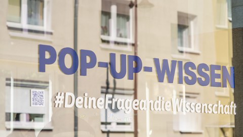 Ein Schaufenster mit der Beklebung POP-UP-WISSEN Hashtag Deine Frage an die Wissenschaft