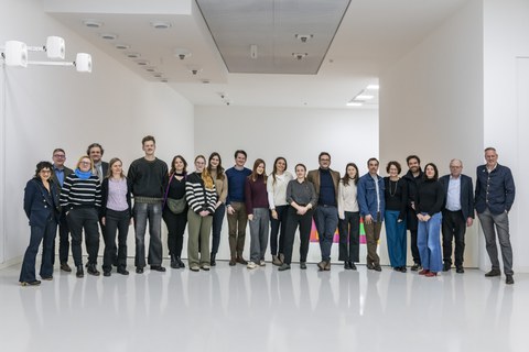 Eine Gruppe von 21 Personen steht für ein Gruppenbild eng beisammen in einem hellen Raum