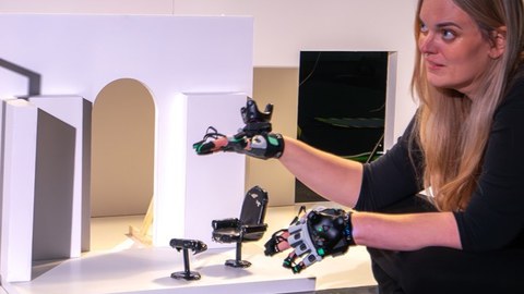 Eine Person sitzt vor einem Modell und bewegt ihre Hände.