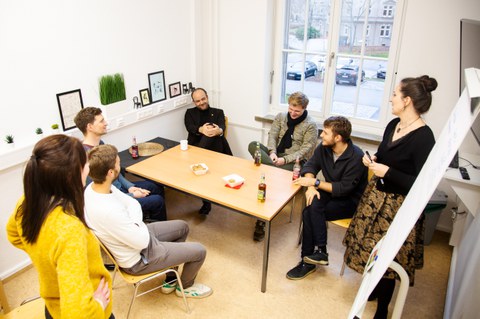 7 Personen im Austausch miteinander um einen Tisch herum