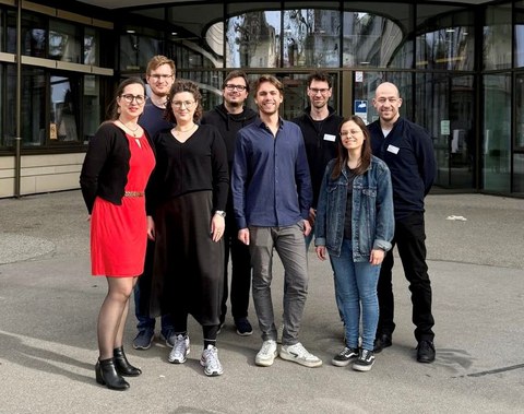 8 Personen vor einem Gebäude auf dem Campus der TU München - v.l.n.r.: Marie-Christin Willemer (Leiterin MITZ), Tutor:innen Julius, Sarah, Eric, Jonas, Raphael und Anne sowie Mathias Bleier-Rox (SP-Programm MITZ)