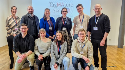 zehn Personen vor dem Banner des internationalen Skills  Lab Symposiums in Mannheim