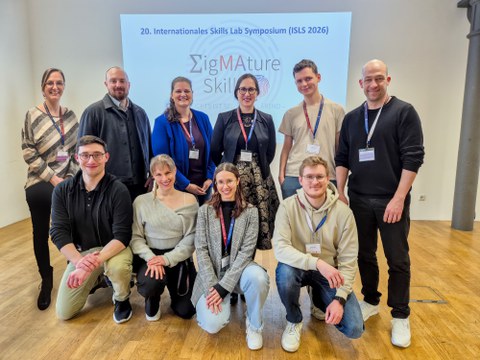 zehn Personen vor dem Banner des internationalen Skills  Lab Symposiums in Mannheim