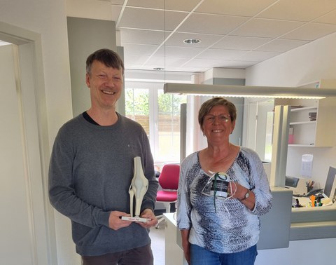 Zwei Personen stehen nebeneinander und lächeln in die Kamera. Eine der beiden hat medizinische Geräte aus ihrer aufgelösten Praxis an das MITZ gespendet.