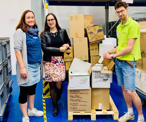 3 Personen stehen vor Materialkisten, v.l.n.r. Christiane Darre-Guhr (Leiterin Lagerwirtschaft UKD), Marie-Christin Willemer (Leiterin MITZ), Raphael Thiele (studentischer Tutor im MITZ)