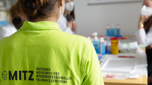 Rückenanischt einer Tutorin im MITZ T-Shirt in der Lehrsituation