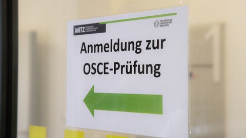 Schild mit grüner Schrift und Aufdruck "Anmeldung zur OSCE-Prüfung"