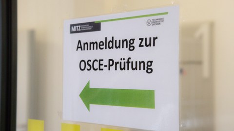 Schild mit grüner Schrift und Aufdruck "Anmeldung zur OSCE-Prüfung"