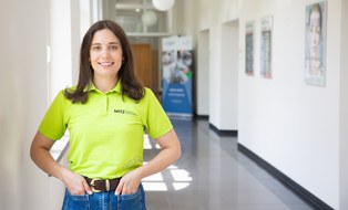 Portrait von Claudia Perge mit grünem MITZ-T-Shirt auf dem Gang im Haus 40