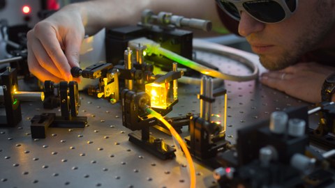 Das Foto zeigt einen jungen Mann in einem Laserlabor.