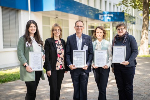 Das Foto zeigt fünf Personen, von denen vier eine Urkunde in der Hand halten.