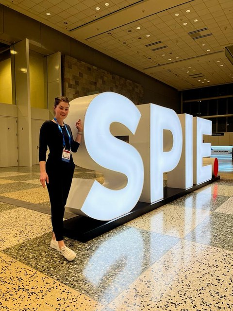 Das Foto zeigt eine junge Frau vor dem Logo der SPIE in San Francisco.