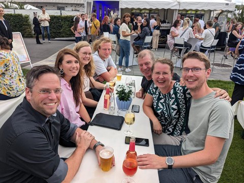 Das Foto zeigt eine Gruppe Personen, die beim UKD Sommerfest an einem Tisch sitzen.