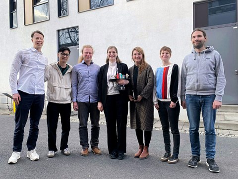 Auf dem Foto sind mehrere Personen zu sehen, die in einer Reihe stehen und in die Kamera schauen.