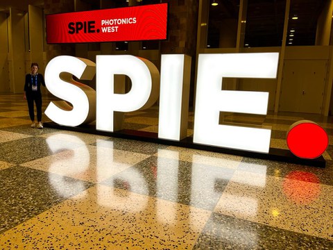 Das Foto zeigt eine junge Frau vor dem Logo der SPIE in San Francisco.