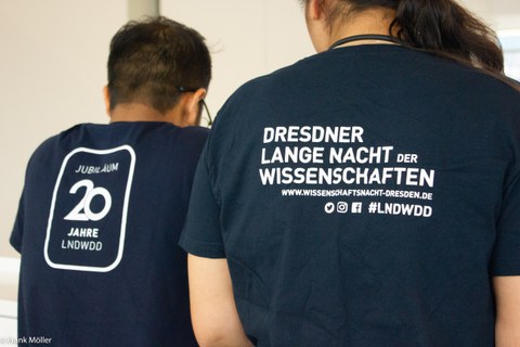 Zwei Personen stehen mit Rücken zu Kamera. Auf dem Rücken des T-Shirts steht Lange Nacht der Wissenschaften 2023