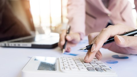 Finger bedient einen Taschenrechner auf einem Schreibtisch