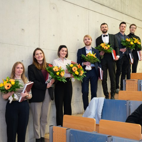 Die Preisträgerinnen und Preisträger mit Blumen aufgereiht im Hörsaal