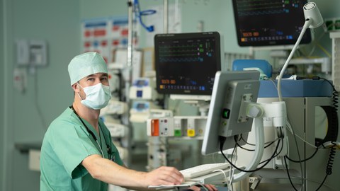 Dr. Jakob Wittenstein (links) in OP-Kleidung an einem Bildschirm.