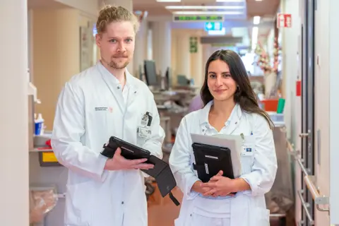Zwei Personen in weißen Kitteln schauen in die Kamera.