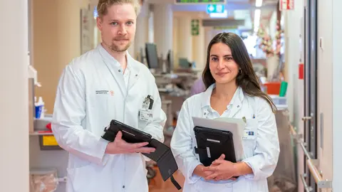 Zwei Personen in weißen Kitteln schauen in die Kamera.