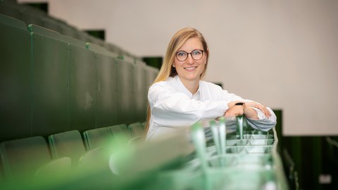 Prof. Carolin Schneider sitzt in einem Hörsaal.
