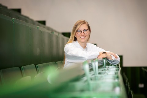 Prof. Carolin Schneider sitzt in einem Hörsaal.