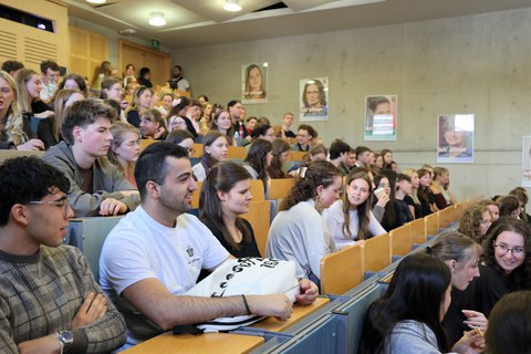 Nahaufnahme junger Menschen in einem voll besetzten Hörsaal. 