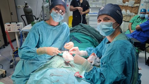 Zwei Chirurginnen sitzen sich am OP-Tisch gegenüber und operieren.