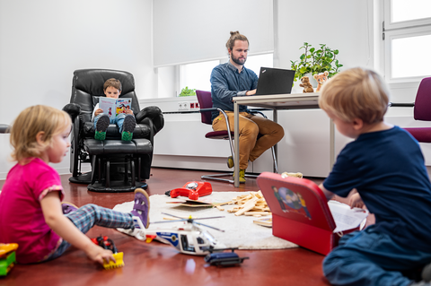 arbeitender Vater und spielende Kinder in einem Raum