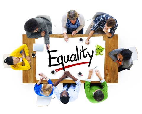 Das Foto zeigt acht Personen, die an einem Tisch sitzen. Auf dem Tisch befindet sich eine weiße Fläche, auf der das Wort "Equality" steht. Das Foto ist aus der Vogelperspektive aufgenommen.