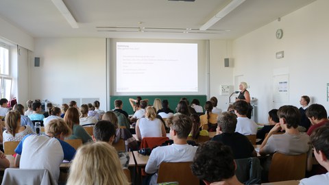 Hörsaal mit vielen Personen vor einer Präsentation 