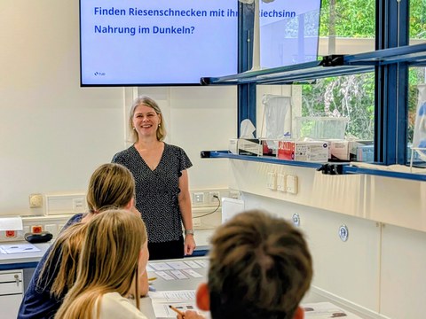 Frau hinter Schülern vor Monitor im Labor