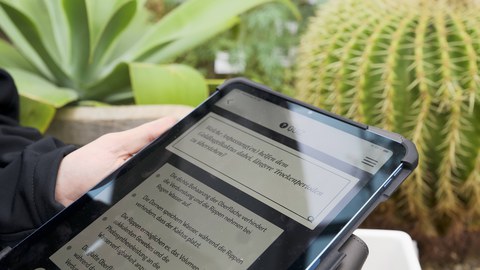 Tablet im Vordergrund; Pflanzen im Hintergrund