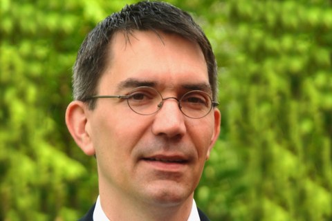 Das Foto zeigt Prof. Michael Hellwig vor einem grünen Hintergrund.