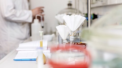 Ein Labortisch mit chemischen Apparaturen und einem Notizbuch für die Ergebnisse