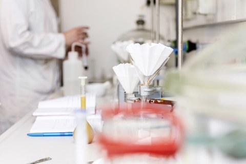 Ein Labortisch mit chemischen Apparaturen und einem Notizbuch für die Ergebnisse