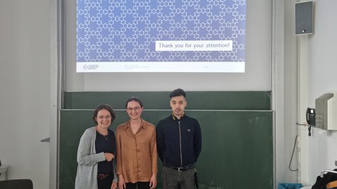 Zwei Frauen und ein Mann stehen vor einer Tafel über der eine Präsentationsfolie gezeigt ist auf der Thank you for your attention steht.