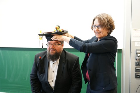 Woman puts PhD hat on man's hat