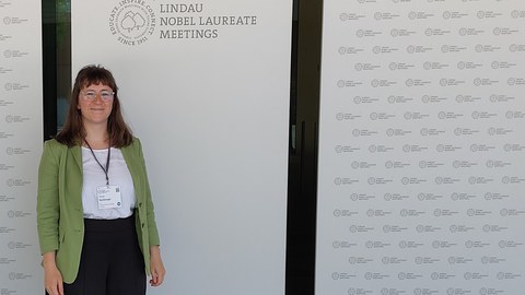 Fraum im Grünen Blazer vor Posterstand