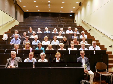 Frontalaufnahme von ca. 30 ehemaligen Studierenden, die in unteren Reihnen des Hörsaals sitzen