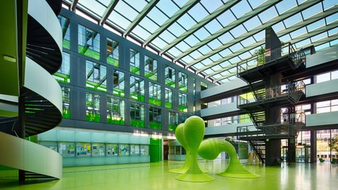 Blick in das Foyer des Andreas-Pfitzmann-Baus der TU Dresden. Der Boden des Foyers ist grün. In der Mitte stehen drei grüne Skulpturen