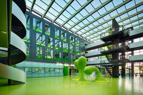 Blick in das Foyer des Andreas-Pfitzmann-Baus der TU Dresden. Der Boden des Foyers ist grün. In der Mitte stehen drei grüne Skulpturen