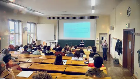 Ein Foto von einem Hörsaal mit Publikum und zwei Vortragenden