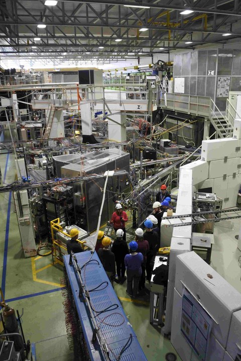 Blick von oben in eine Experimentierhalle auf eine Gruppe von Studierenden mit Helmen