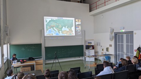 Schülergruppe in einem Hörsaal bei einer Videokonferenz