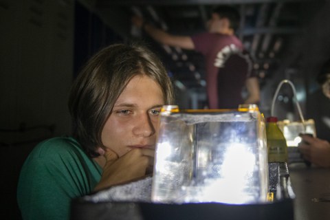 Eine Schülerin beobachtet ein Experiment mit einer Nebelkammer