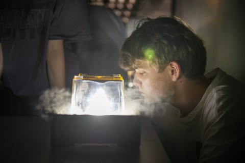 Ein Schüler beobachtet ein Experiment in einer Nebelkammer